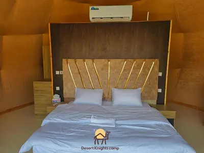 a bedroom with a large bed with a wooden headboard at Desert Knights camp in Wadi Rum