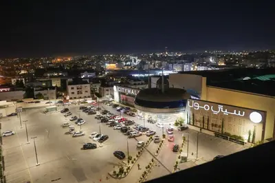 a parking lot with cars parked in front of a building at Jeddah Homes Boutique Hotel in Amman