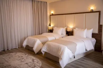 two beds in a hotel room with white sheets at Jeddah Homes Boutique Hotel in Amman