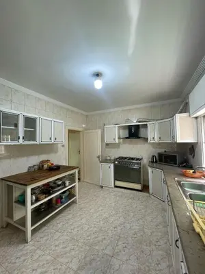 a large kitchen with white cabinets and a counter at Decapolis in Irbid