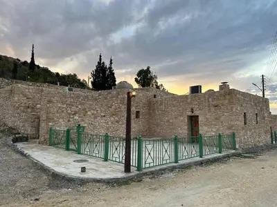 a stone building with a green fence in front of it at Tafileh-Sila'a Heritage Village in At-Tafilah
