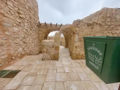 an old stone building with a green trash can at Tafileh-Sila'a Heritage Village in At-Tafilah
