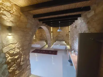 a bedroom with two beds and a stone wall at Tafileh-Sila'a Heritage Village in At-Tafilah