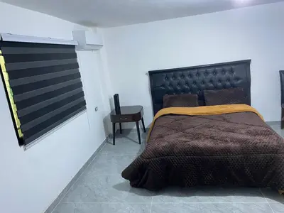 a bedroom with a bed with a black headboard and a table at huseein rooms in Jerash