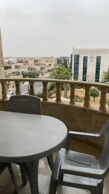 a table and chairs on a balcony with a view at Abdoun Apartment in Amman
