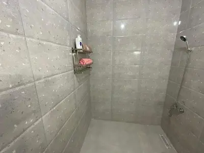 a bathroom with a shower with gray tiled walls at Black IRIS in Jerash