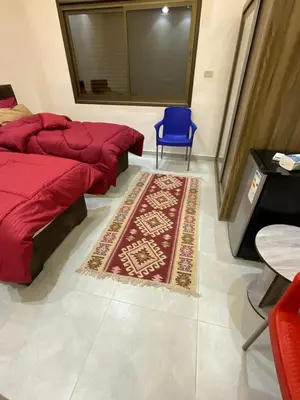 a bedroom with two beds and a blue chair and a rug at Black IRIS in Jerash