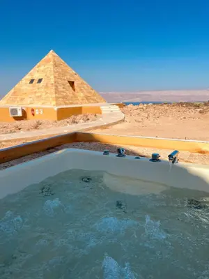 a pool of water with a pyramid in the background at Deadsea OCTAGON in Madaba