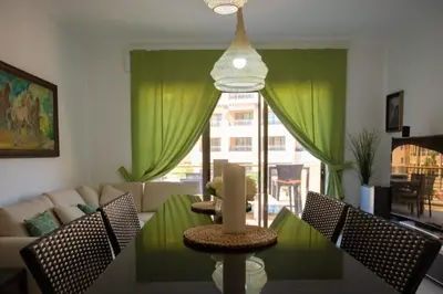a living room with a table and green curtains at Sunset apartment in Samarah Dead Sea resort in Sowayma