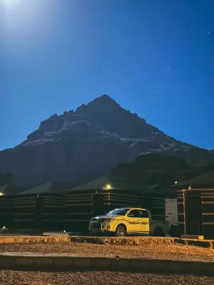 a yellow truck parked in front of a mountain at Full moon camp in Wadi Rum