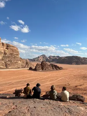 a group of people sitting on a rock in the desert at Full moon camp in Wadi Rum