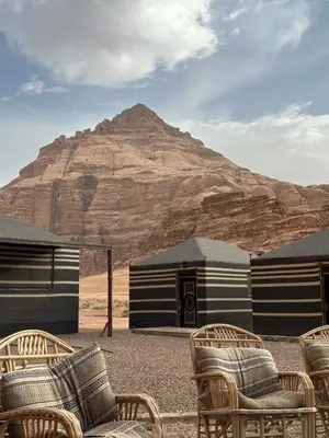 a group of chairs and tents with a mountain in the background at Full moon camp in Wadi Rum