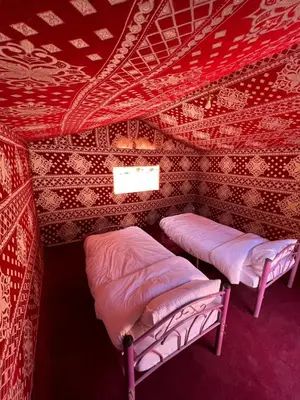 two beds in a room with a red ceiling at Wadi Rum Best Tours in Wadi Rum