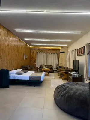 a bedroom with two beds and a living room with a couch at Oak Farm Ajloun مزرعة البلوط عجلون in Ajloun
