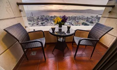 a table with a vase of flowers in a room with a window at De-Lara hotel in Aqaba