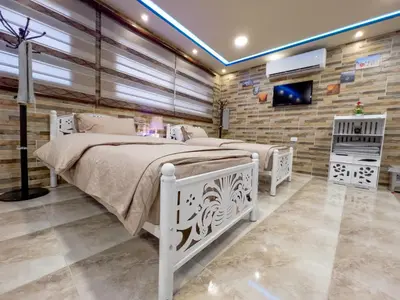 a bedroom with two beds and a tv on a brick wall at PETRA ROYAL HOUSE in Wadi Musa
