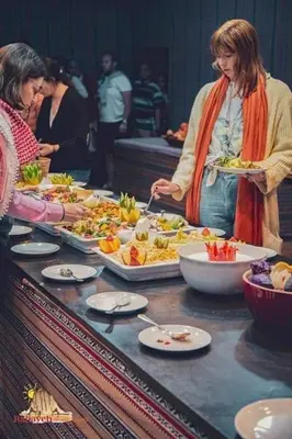 a group of people standing around a table with plates of food at Lulua luxury camp in Wadi Rum