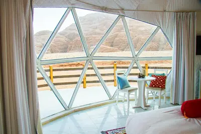 a bedroom with a large window with a table and chairs at Desert Season Luxury Camp Wadi Rum Boutique Tents & Stargazing in Wadi Rum