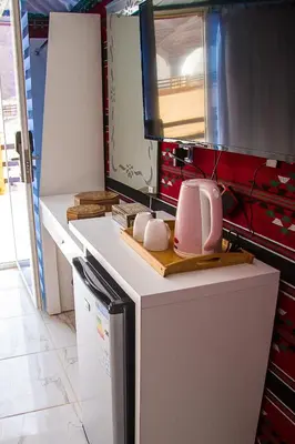 a kitchen with a white refrigerator and a pink toaster at Desert Season Luxury Camp Wadi Rum Boutique Tents & Stargazing in Wadi Rum