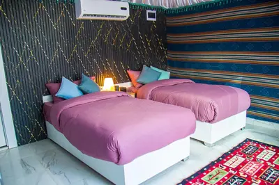 two beds in a room with purple blankets and pillows at Desert Season Luxury Camp Wadi Rum Boutique Tents & Stargazing in Wadi Rum
