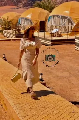 a woman in a white dress walking down a street at RUM DREAM BUBBLES lUXURY CAMP in Wadi Rum
