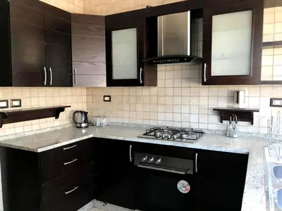 a kitchen with black cabinets and a stove top oven at MK6 - Two bedroom Apartment in Amman