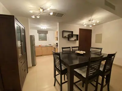 a kitchen and dining room with a table and chairs at Lovely first floor tow bed rooms overviewing circular pool for families only in Talabay Aqaba in Aqaba