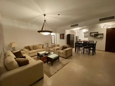 a living room with a couch and a table at Lovely first floor tow bed rooms overviewing circular pool for families only in Talabay Aqaba in Aqaba