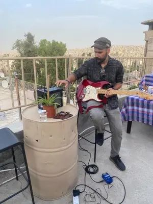 a man is playing a guitar on a patio at Darna Hostel in Amman