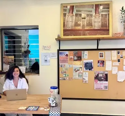 a woman sitting at a desk with a laptop at Darna Hostel in Amman