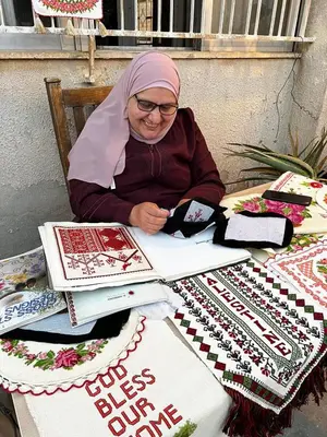 a woman sitting at a table with a table of quilts at Darna Hostel in Amman