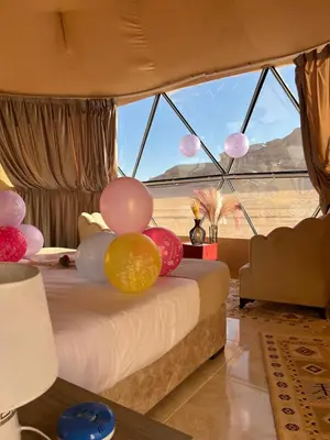 a bed with balloons on it in a room at Queen's Magic Camp in Wadi Rum