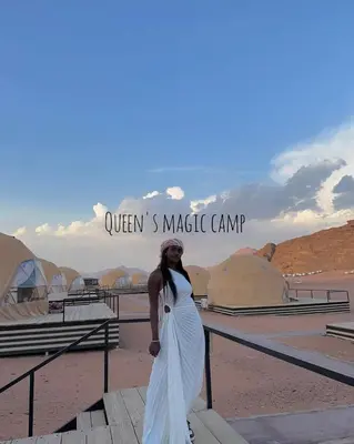 a woman in a white dress looking at the desert at Queen's Magic Camp in Wadi Rum