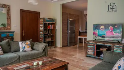 a living room with a couch and a flat screen tv at Maison Gaia, A Stylish Apartment in the heart of Amman in Amman