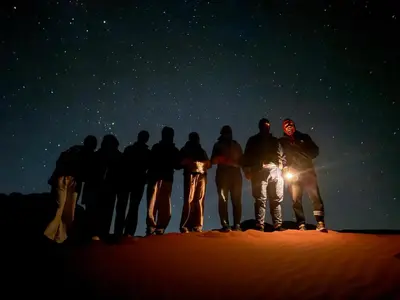 a group of people standing in the desert at night at Magic Bedouin Star in Wadi Rum