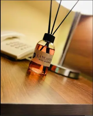 a bottle of alcohol sitting on a table with a phone at LANCASTER HOTEL APARTMENTS DAHIET ALRASHEED in Amman