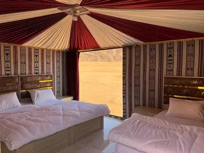 a bedroom with two beds and a large window at Wadi Rum Sand Camp in Disah