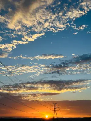 a sunset with electricity transmission towers in the foreground at Wadi Al-Wala View Camp in Madaba