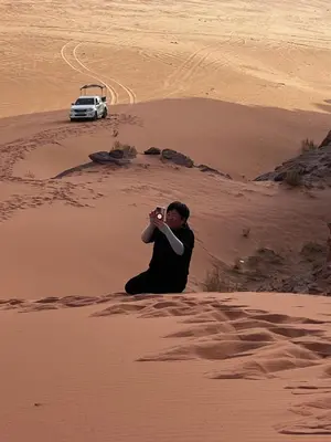 a man taking a picture of a car in a desert at Jori Luxury Camp in Wadi Rum