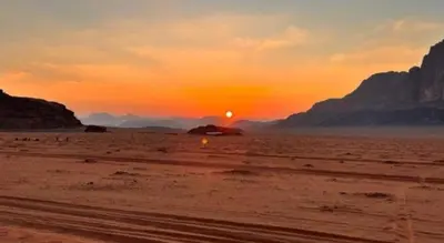 a sunset in the desert with the sun in the distance at Awad Bedouin camp in Wadi Rum