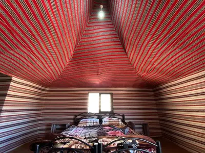 a room with a red ceiling with a bed in it at Awad Bedouin camp in Wadi Rum