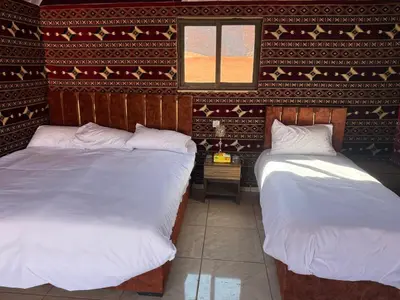 two beds in a room with a wall at Desert Nights Camp in Wadi Rum