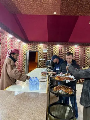 a group of people standing around a table with food at Desert Nights Camp in Wadi Rum