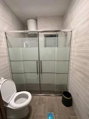a bathroom with a toilet and a glass shower at modern apartment in abdoun-amman in Amman