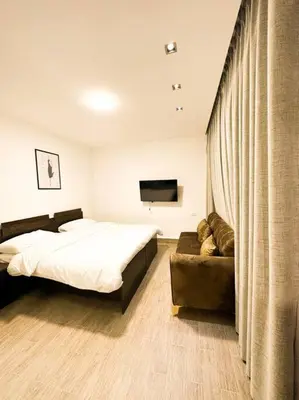 a bedroom with a bed and a couch and a television at central apartment for rent 31 in Umm Uthainah