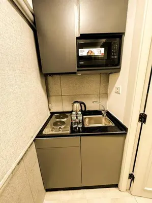 a small kitchen with a sink and a microwave at central apartment for rent 31 in Umm Uthainah