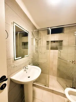 a bathroom with a sink and a glass shower at central apartment for rent 30 in Umm Uthainah