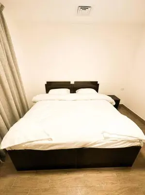 a bedroom with a large bed with white sheets at central apartment for rent 30 in Umm Uthainah