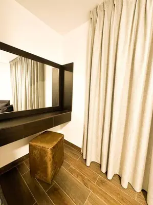 a room with a mirror and a ottoman next to a curtain at central apartment for rent 28 in Umm Uthainah