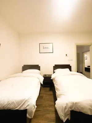 two beds with white sheets and a sign that reads love at central apartment for rent 24 in Umm Uthainah